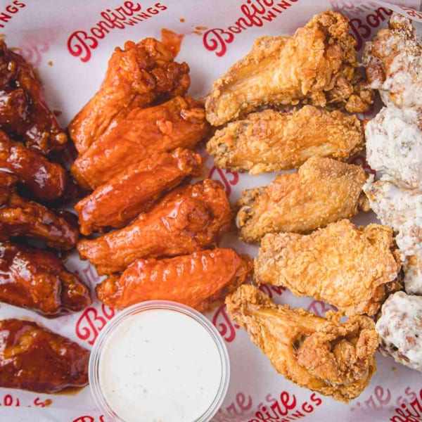 A variety of Bonfire Wings, including BBQ, buffalo, crispy, and garlic parmesan, with a side of ranch.