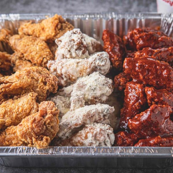 A foil tray filled with three varieties of Bonfire Wings: crispy, parmesan, and buffalo.