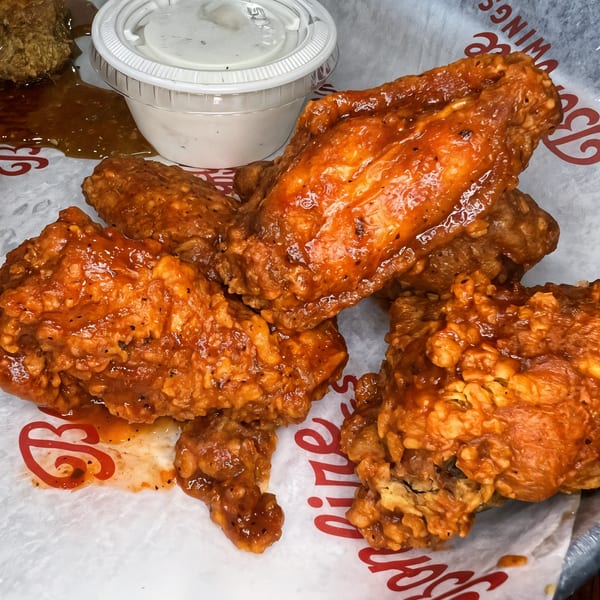 Bonfire Wings' crispy, saucy chicken wings with a side of ranch dressing and a sweet dipping sauce.