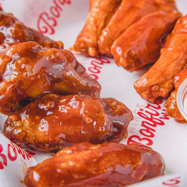 Close-up of Bonfire Wings' saucy chicken wings, some in barbecue and some in buffalo sauce.
