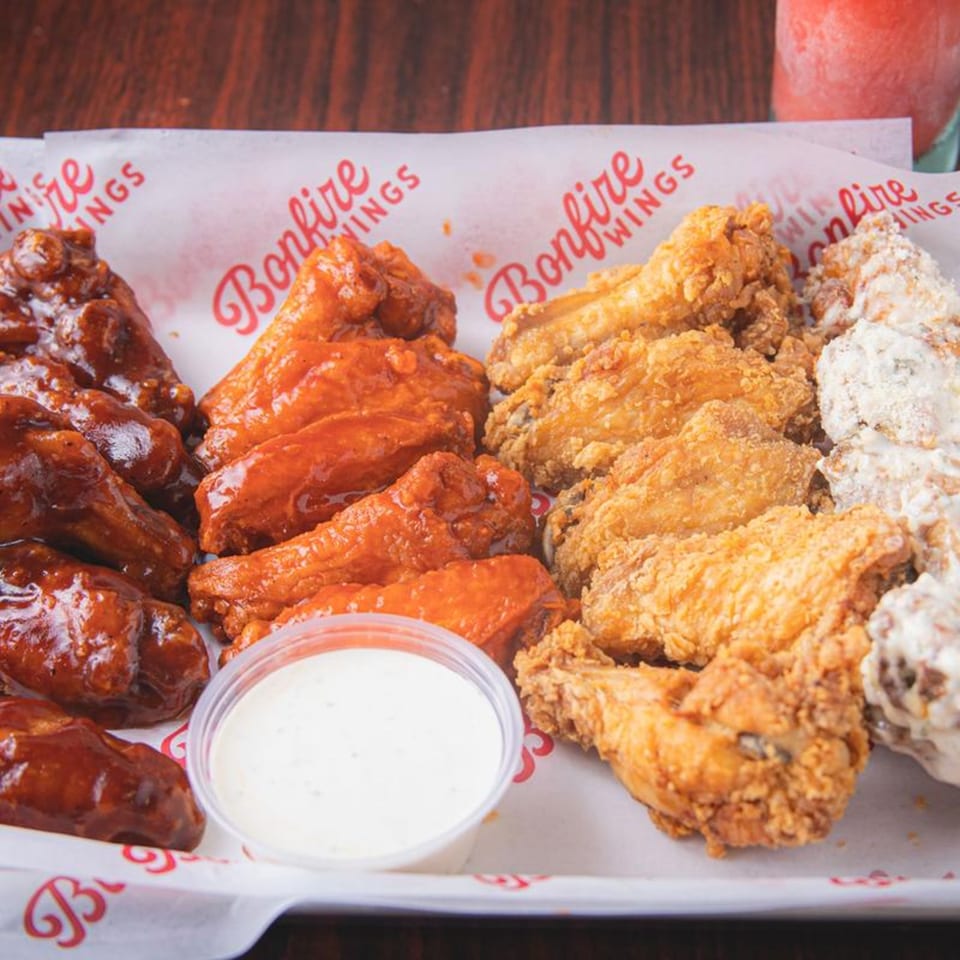 A tray of Bonfire Wings with three different flavors: BBQ, buffalo, and garlic parmesan, with ranch.